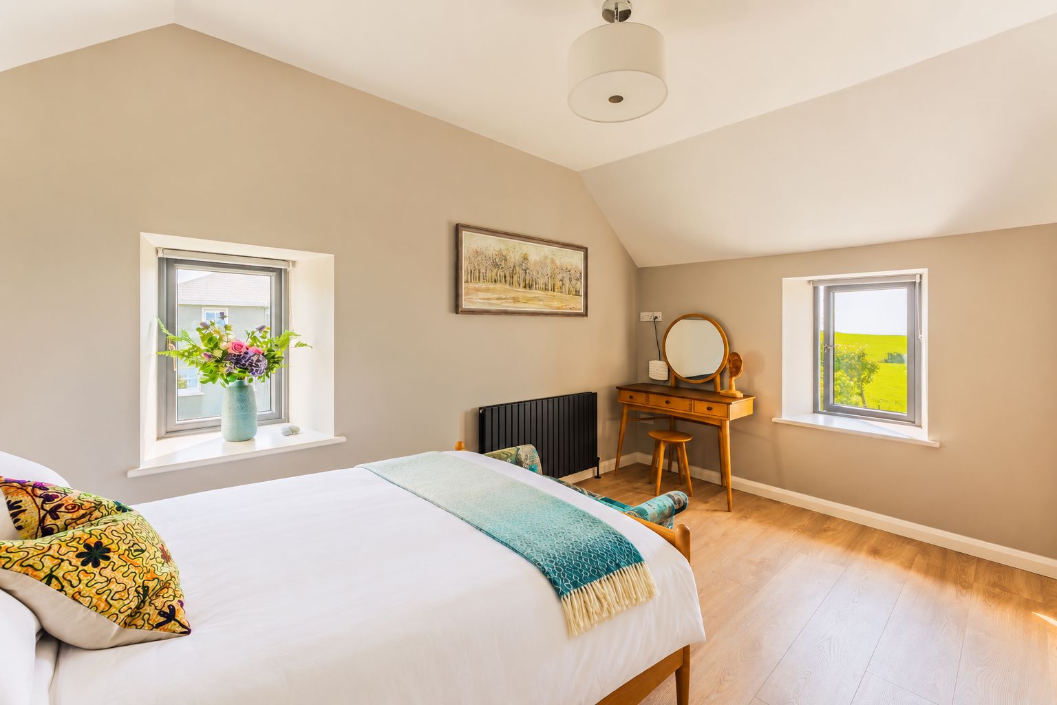 A bedroom with a bed, dresser, and two windows.