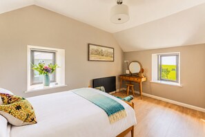 A bedroom with a bed, dresser, and two windows.