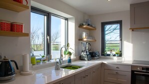 A modern kitchen with a large window, a sink, a kettle, and a blender.