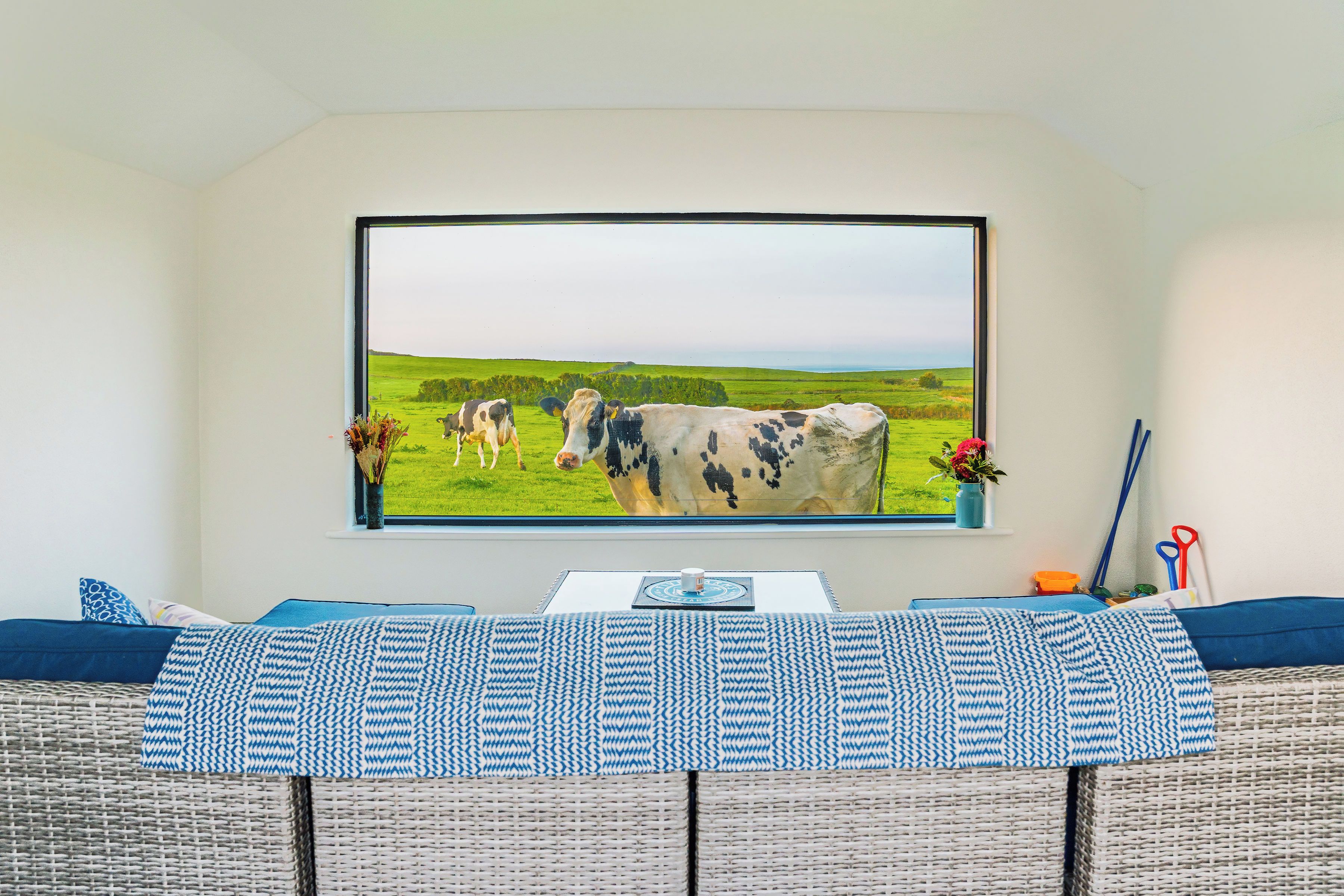A room with a large window displaying a landscape painting of cows.