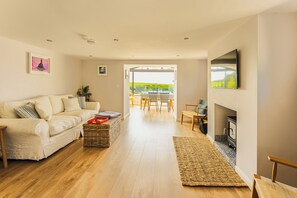 A modern living room with a sofa, a dining area, and a fireplace. - 5-star rural escape hidden between the coastal towns of Kinsale and Clonakilty, (Clonakilty)
