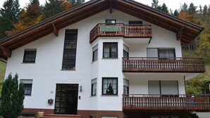 A two-story building with a balcony, a door, and windows.