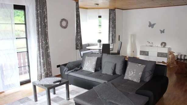A modern living room with a grey sofa, a small table, and a patterned rug.