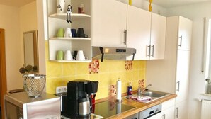 A compact kitchen with white cabinets, a microwave, a coffee maker, and a toaster. - Holiday beach chair - centrally located in Norddeich (Norden)