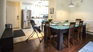 Une cuisine moderne avec un coin repas, des appareils en acier inoxydable et une table à manger pour quatre personnes.