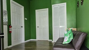A hallway with green walls, white doors, and a brown leather bench with a green pillow. - La Bwizan Inn Apt. #1 (Laborie)