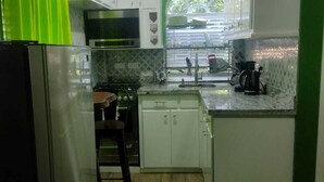 A compact kitchen with white cabinets, a stainless steel refrigerator, and a microwave. - La Bwizan Inn Apt. #1 (Laborie)