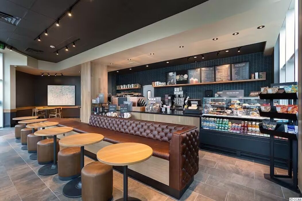 Un café moderne avec un long comptoir, un espace salon et un présentoir pour afficher le menu.