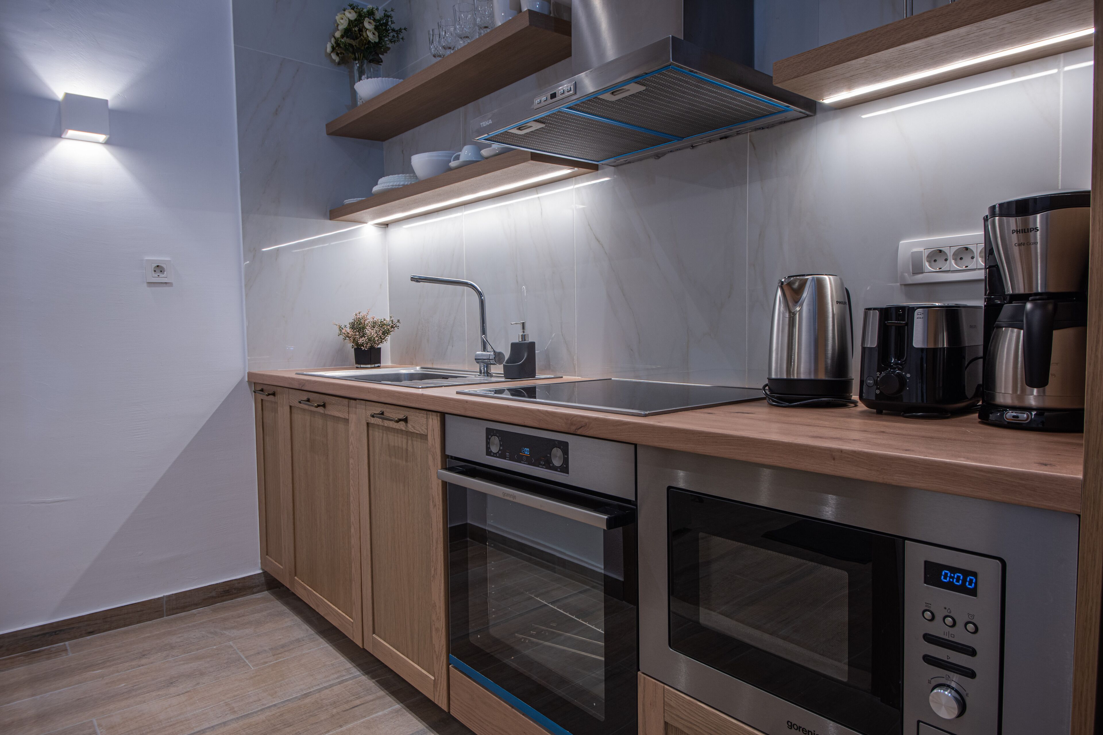 A modern kitchen with built-in appliances, a sink, and a coffee maker.