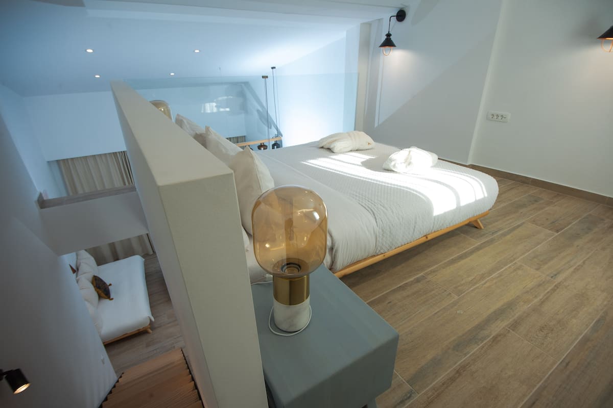 Un dormitorio moderno con una cama grande, una mesita de noche con lámpara y suelo de madera.