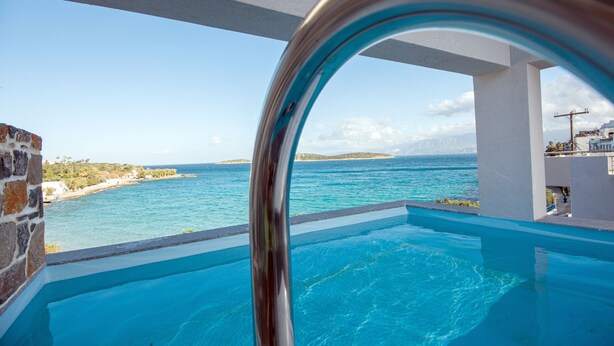 A clear view of a swimming pool with a view of the sea and a rocky coastline.
