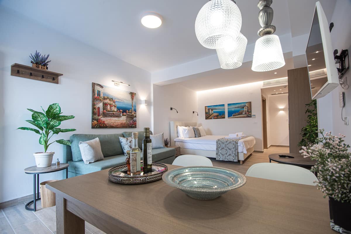 Una sala moderna con un sofá, una mesa de comedor con un tazón, y una cama al fondo.