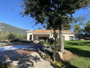 A modern house with a patio, a swimming pool, and a mountain backdrop. - Beautiful new 180-square-meter villa with a pool terrace and a 2,500-square-meter wooded garden (Roquefort-les-Pins)
