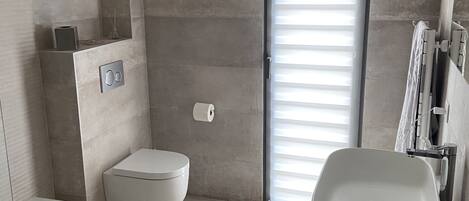 A modern bathroom with a bathtub, toilet, and sink.