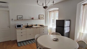 A compact kitchen with a microwave, sink, and dining area with chairs. - 2-bedroom, 4-guest apartment in historic area of Trieste in 19th century style (Trieste)