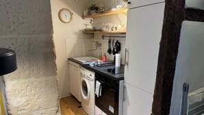 Een compacte keuken met een wasmachine, oven en houten planken boven het aanrecht.