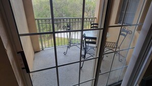 Un balcon avec une balustrade en métal, une petite table et deux chaises.