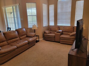 A living room with a brown leather sofa, a recliner, and a TV on a wooden stand. - Large 2 Bedroom 2 Bath Condo 10 Miles from Parks Sleeps 6 (Davenport)