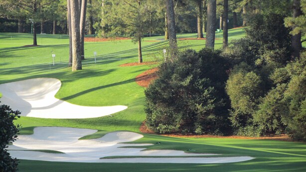 A golf course with sand bunkers, trees, and a well-maintained green. - Masters Oasis Tournament Rental (Evans)