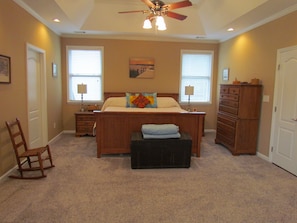 A bedroom with a bed, dresser, chair, and a ceiling fan. - Masters Oasis Tournament Rental (Evans)