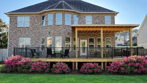 A two-story house with a covered patio and a brick exterior. - Masters Oasis Tournament Rental (Evans)