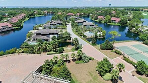Ein Resort mit mehreren Gebäuden, einem See und Tennisplätzen.
