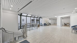 Ein geräumiger, moderner Innenraum mit hoher Decke, einer Treppe und Blick ins Freie.
