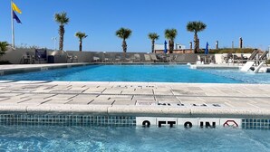 Ein Pool mit klarem, blauem Wasser, umgeben von Palmen und Liegestühlen.