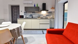 Cocina moderna con comedor, que presenta un sofá rojo y una mesa con sillas.