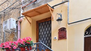 Un muro de piedra con una escalera metálica que conduce a una puerta de madera.