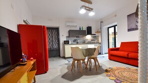 Un espacio habitable compacto con cocina, comedor y un sofá rojo.