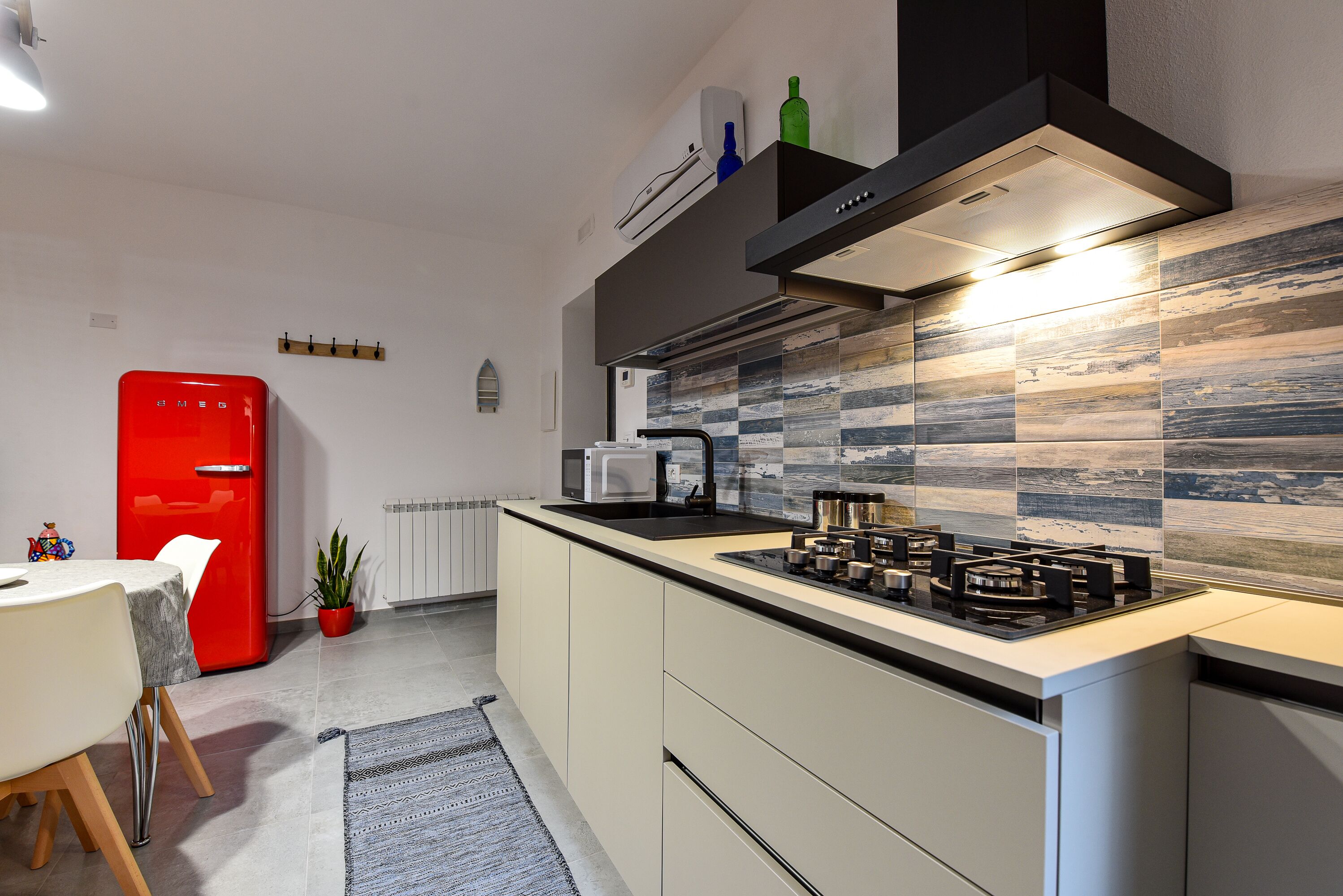 Eine moderne Küche mit einem Gasherd, einem roten Kühlschrank und einer Mikrowelle.
