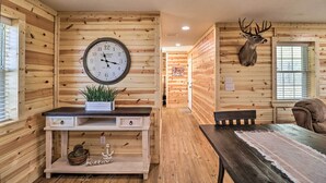 A wooden interior with a large wall clock, a mounted deer head, and a dining area with a table and chairs. - Greers Ferry Home on 40 Acres 1/4 Mi to Lake! (Greers Ferry)