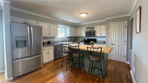 A modern kitchen with stainless steel appliances, wooden flooring, and a central island with bar stools. - POOL house with FENCED Yard for Pets, by the ARK Encounter, Airport, Cincinnati (Independence)