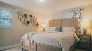 Une chambre avec un lit en bois, une décoration murale composée de motifs circulaires, une lampe de chevet et une fenêtre avec des rideaux.