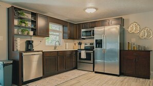 Une cuisine moderne avec des meubles en bois foncé, des appareils électroménagers en acier inoxydable et une fenêtre qui laisse entrer la lumière naturelle.