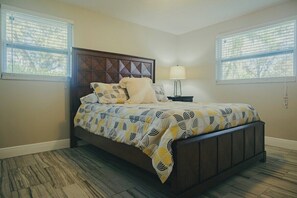 A bedroom with a dark wood bed, patterned bedding, two bedside tables with lamps, and windows with blinds. - 3bdr/2bth Lake Home Tampa/LUTZ close to all (Lutz)