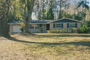 A single-story house with a garage, surrounded by trees and a grassy yard. - 3bdr/2bth Lake Home Tampa/LUTZ close to all (Lutz)