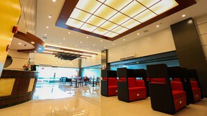A hotel lobby with a reception desk, seating area with red chairs, and a large skylight. - Hotel Sogo Macapagal  (Parañaque)