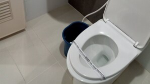 A bathroom with a white sink, a toilet, and a blue bucket. - Hotel Sogo Macapagal  (Parañaque)