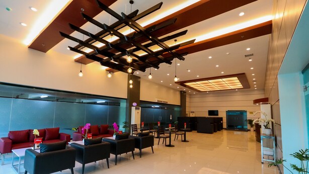 A modern lobby with a red sofa, black chairs, and a reception desk. - Hotel Sogo Macapagal  (Parañaque)