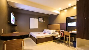 A hotel room with a bed, a desk, a chair, a TV, and a small table. - Hotel Sogo Macapagal  (Parañaque)