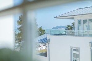 A modern building with a balcony overlooking a body of water and a distant island.