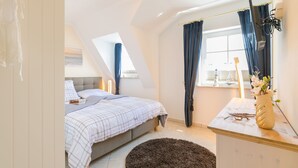 Un dormitorio con cama, mesita de noche y ventana con cortinas.
