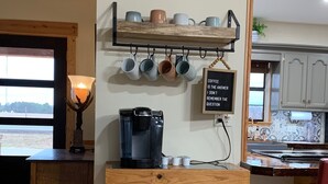 A coffee station with a coffee machine, mugs, and a sign.