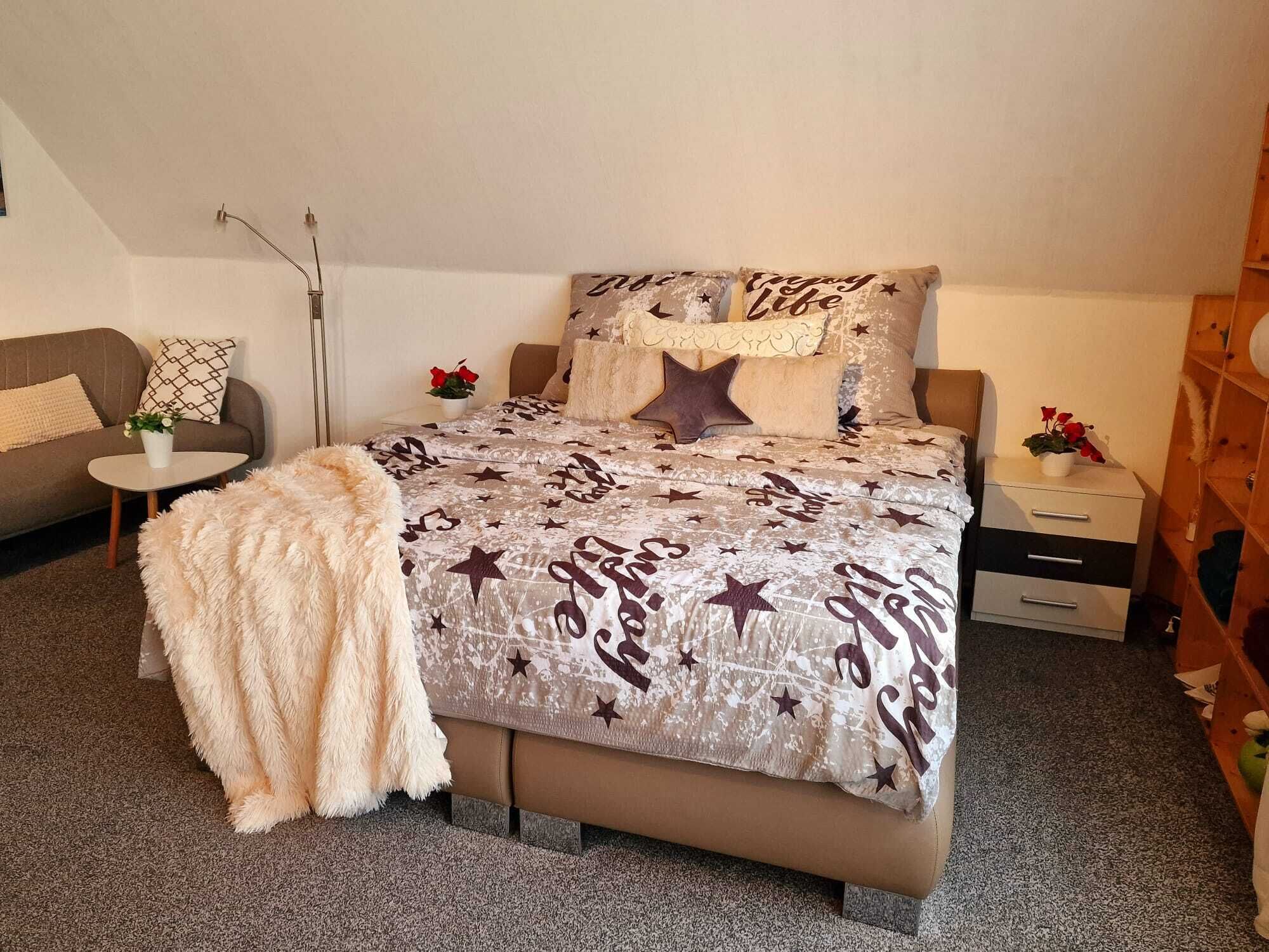 Une chambre à coucher avec un lit, un canapé, une petite table et une table de chevet.