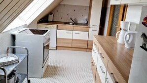Une cuisine compacte équipée d’une cuisinière intégrée, d’un évier et d’une machine à café.