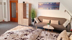 Une pièce chaleureuse avec un plafond en bois, un canapé marron, une petite table ronde et une grande fenêtre donnant sur un pont.