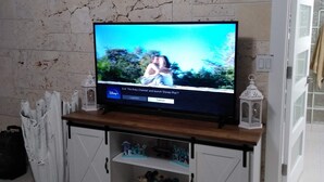 A television on a wooden stand with a marble wall behind it. - Viamarhe-3/1 Ground Level Oceanfront home w/Kayaks, Yard Games & More (Marathon)