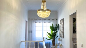 A grand hallway with a chandelier, a staircase, and a large window. - Sunshine Villa (Faro)